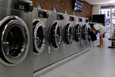 Row of brand new Speed Queen front-loading washers along the exposed brick wall at Fresh Fold Brooklyn