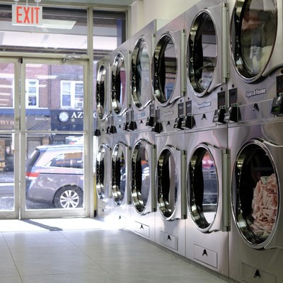 Wall of stacked Speed Queen dryers beside the glass storefront at Fresh Fold Brooklyn